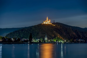 A castle on a hill overlooking a calm lake at night. - Burgenheimat (Rhens)
