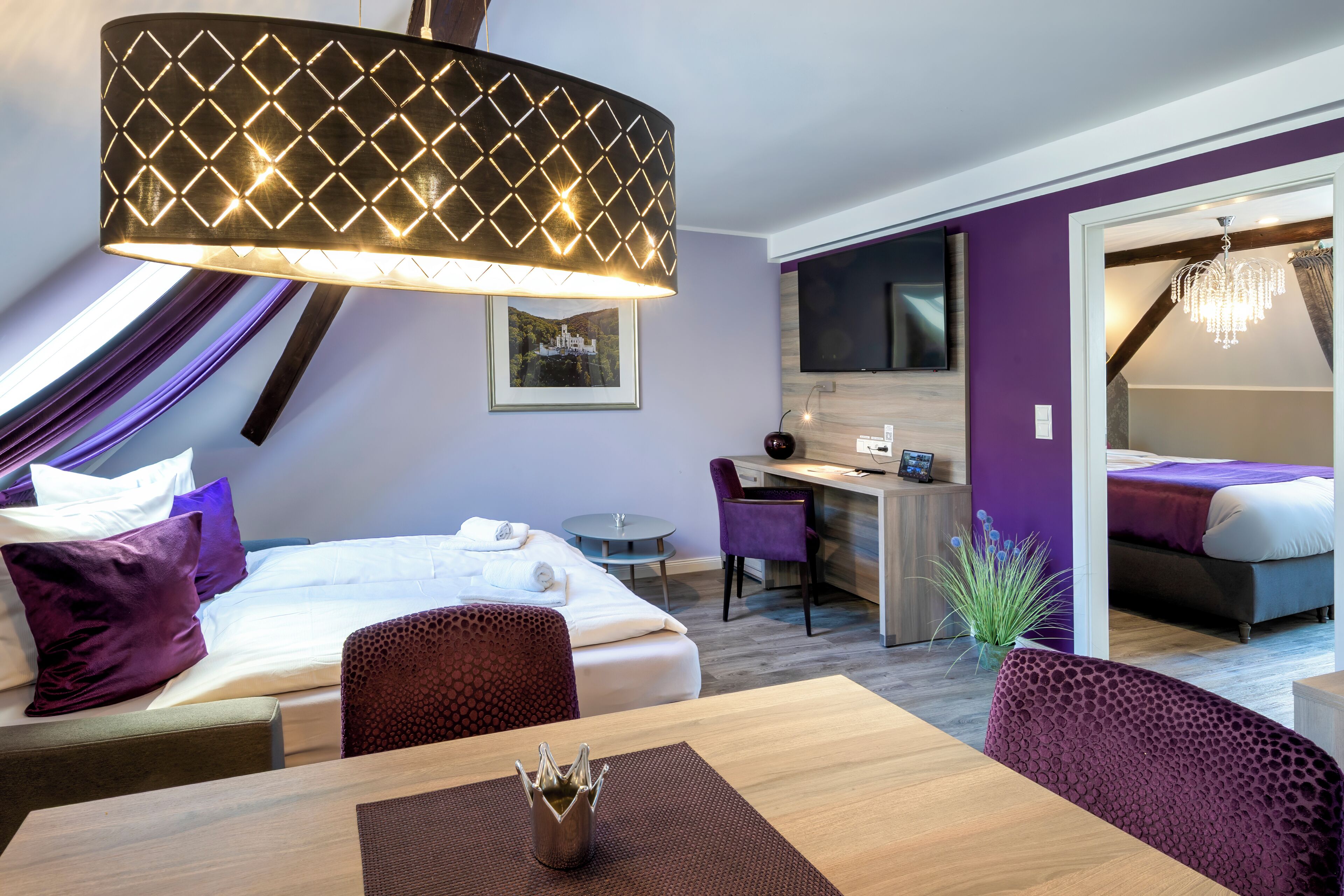 A hotel room with a bed, desk, chair, and a dining table with a decorative centerpiece.