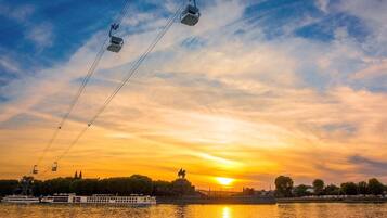 A sunset over a river with a boat and a statue in the background.