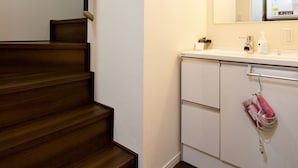 Una escalera conduce a un dormitorio con una pared blanca y un suelo de madera.