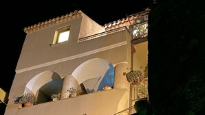 A building with a sloped roof, a balcony with potted plants, and a window. - Elegant Holiday Home, in the Village (Badolato)