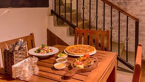 A dining area with a wooden table set for a meal, a pizza, and various dishes. A chalkboard with inspirational quotes is visible on the wall. - Spice Ella (Ella)