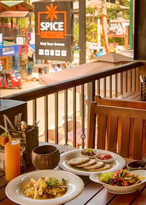 Un restaurante con terraza, varios platos en la mesa y un letrero que dice 'SPICE'.