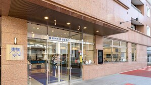 A building entrance with a glass door, a sign with Japanese characters, and a red tactile paving on the sidewalk. - Toyoko Inn Kumagaya Station Kita (Kumagaya)
