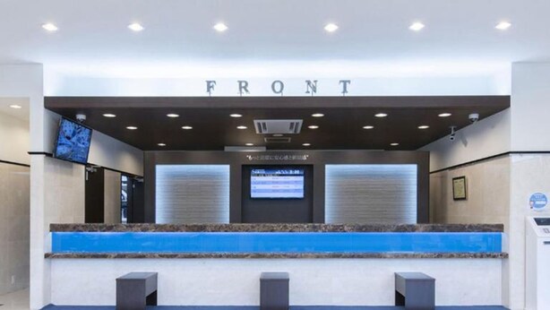 A reception area with a counter labeled "FRONT" and a digital screen displaying information. - Toyoko Inn Kumagaya Station Kita (Kumagaya)