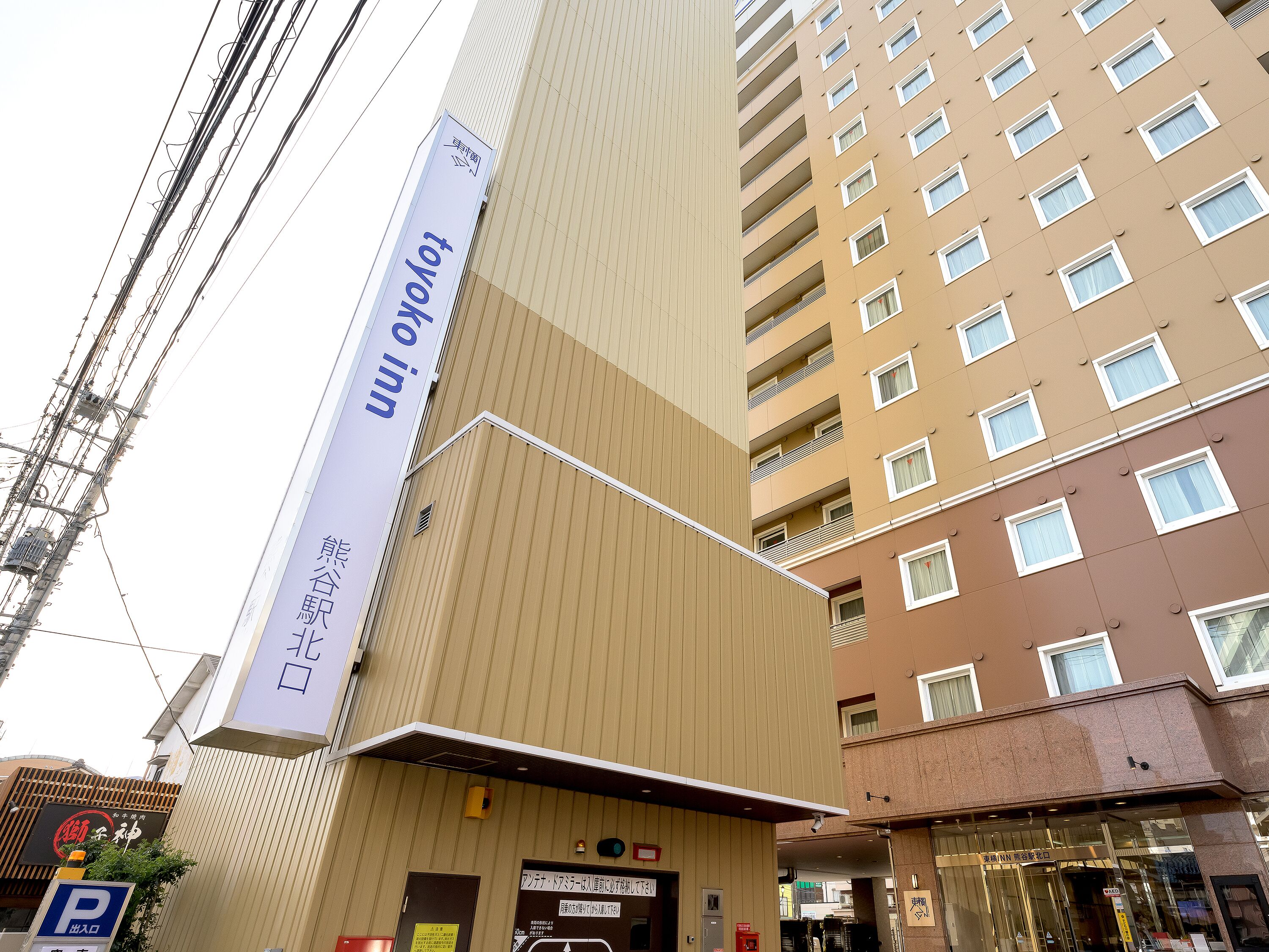 A multi-story building with a prominent vertical sign advertising a hotel.