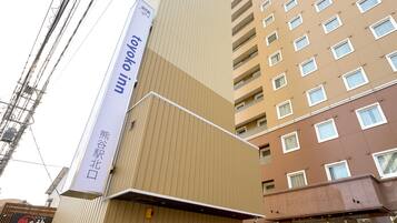 Un edificio de varios pisos con un letrero vertical llamativo que anuncia un hotel.