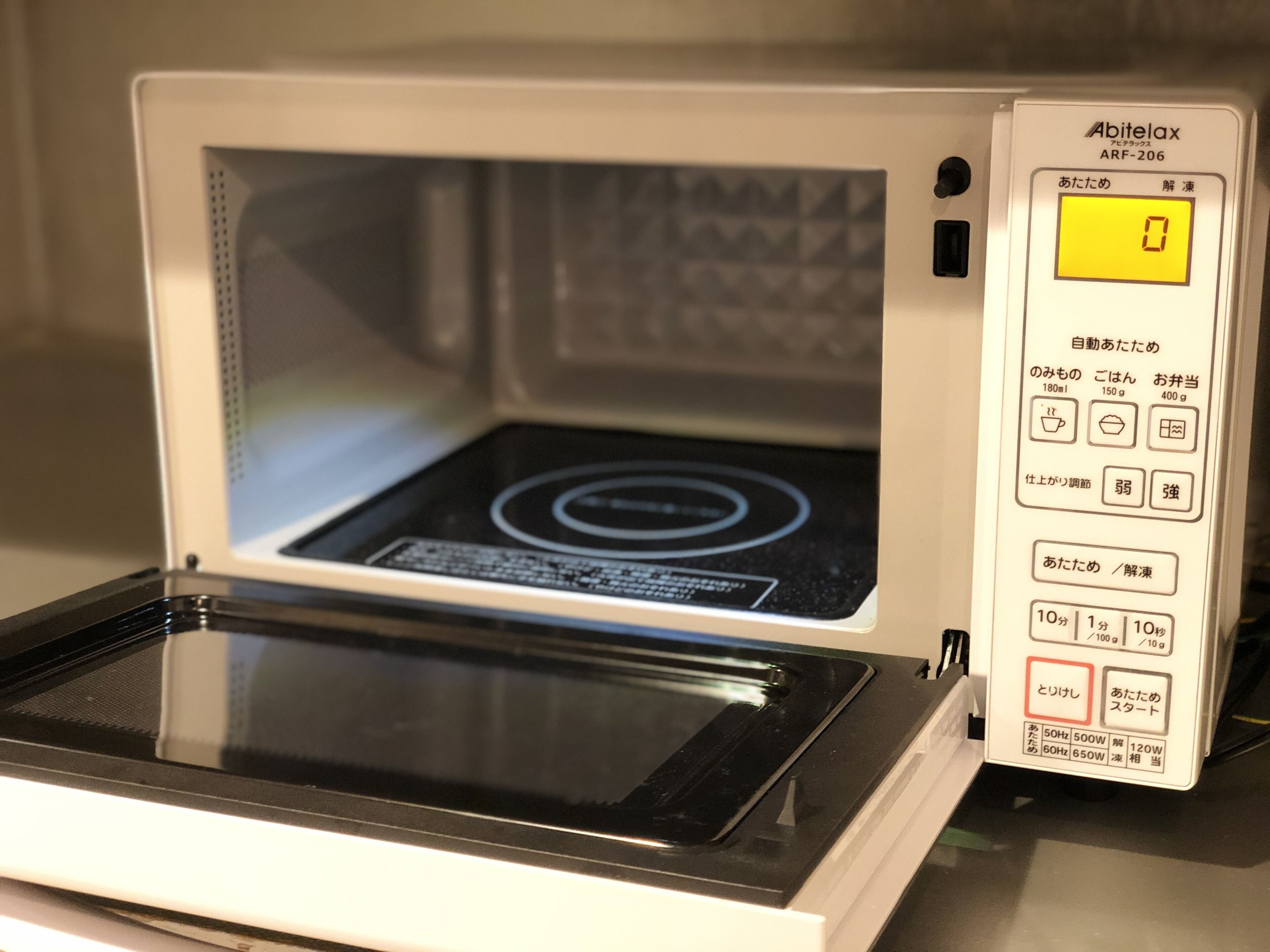 A microwave with a digital display, control panel, and a glass turntable.