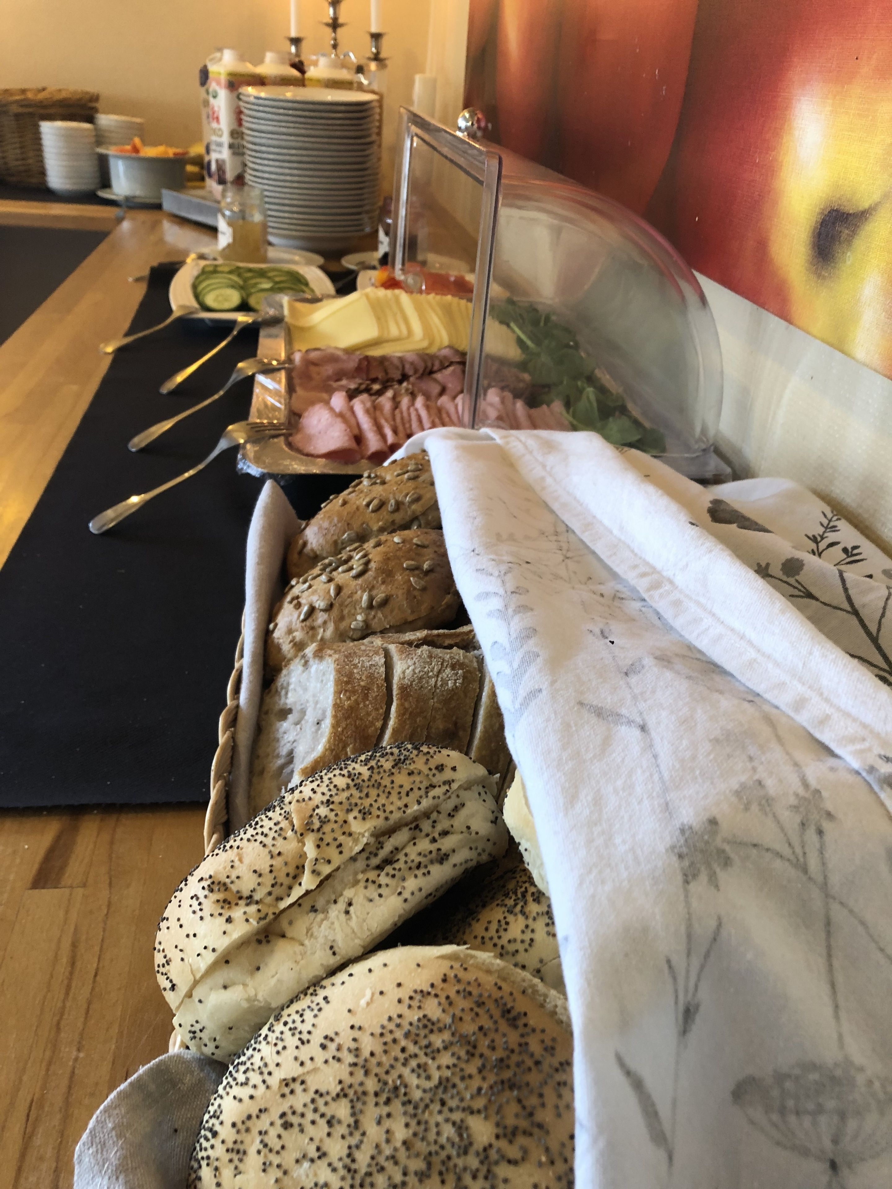 A buffet table with various breads, a salad, and a meat platter.