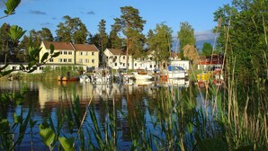Un lac paisible où flottent des bateaux, entouré de maisons et d’arbres.