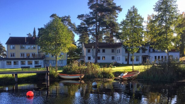 Un lac paisible, parsemé de bateaux, entouré de bâtiments résidentiels et d’arbres.