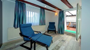 A room with two blue armchairs, a radiator, wooden flooring, and a view of an outdoor area. - Haus Mittelrhein (Rhens)