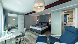 A modern hotel room with a bed, two chairs, a desk, and a large window. - Haus Mittelrhein (Rhens)