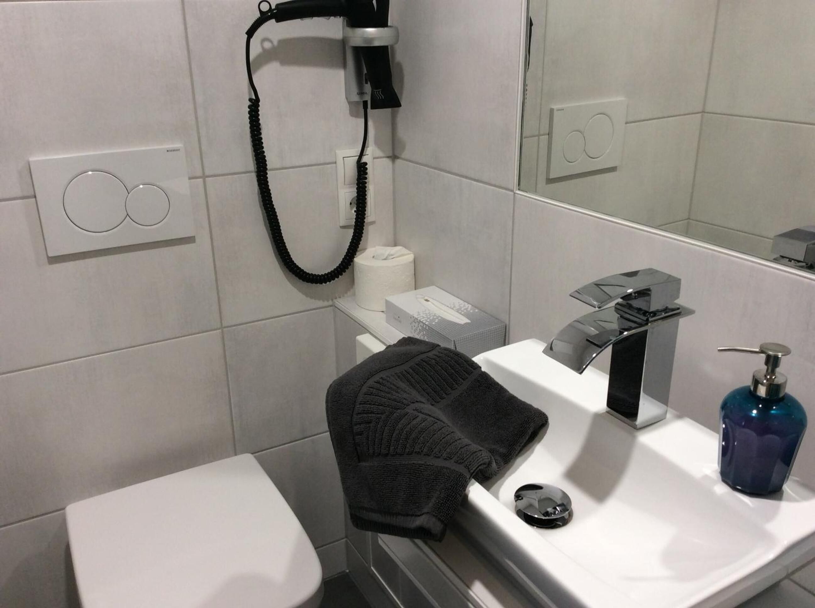A modern bathroom with a toilet, sink, and mirror.