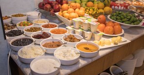 Un bufé con diversas opciones de comida, incluyendo frutas, verduras y diferentes tipos de salsas y untables.