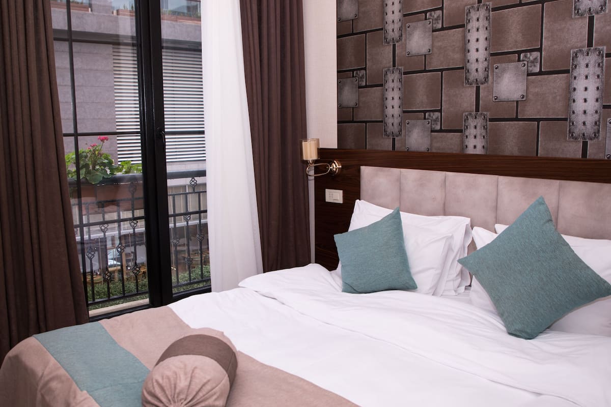Een hotelkamer met een bed, uitzicht buiten door een raam en een muur met een baksteenpatroon.