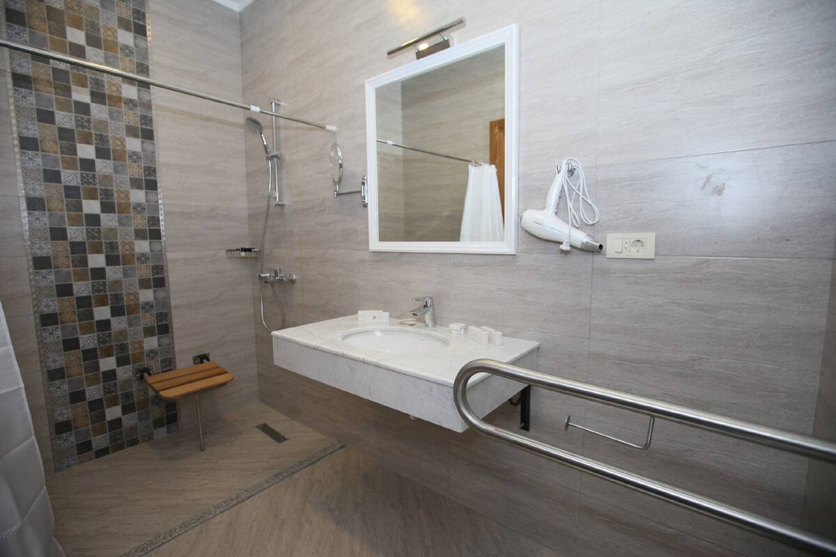 Een moderne badkamer met een groot wastafel, een spiegel en een douchehoek.