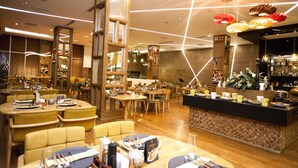 Un ristorante con tavoli e sedie di legno, un bancone con prodotti alimentari e lampade a sospensione.