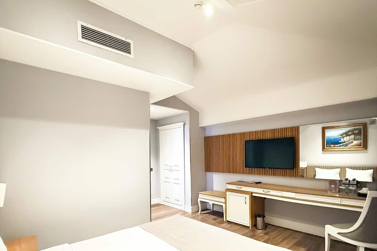 A modern hotel room with a bed, desk, chair, TV, and a view of the outdoors.