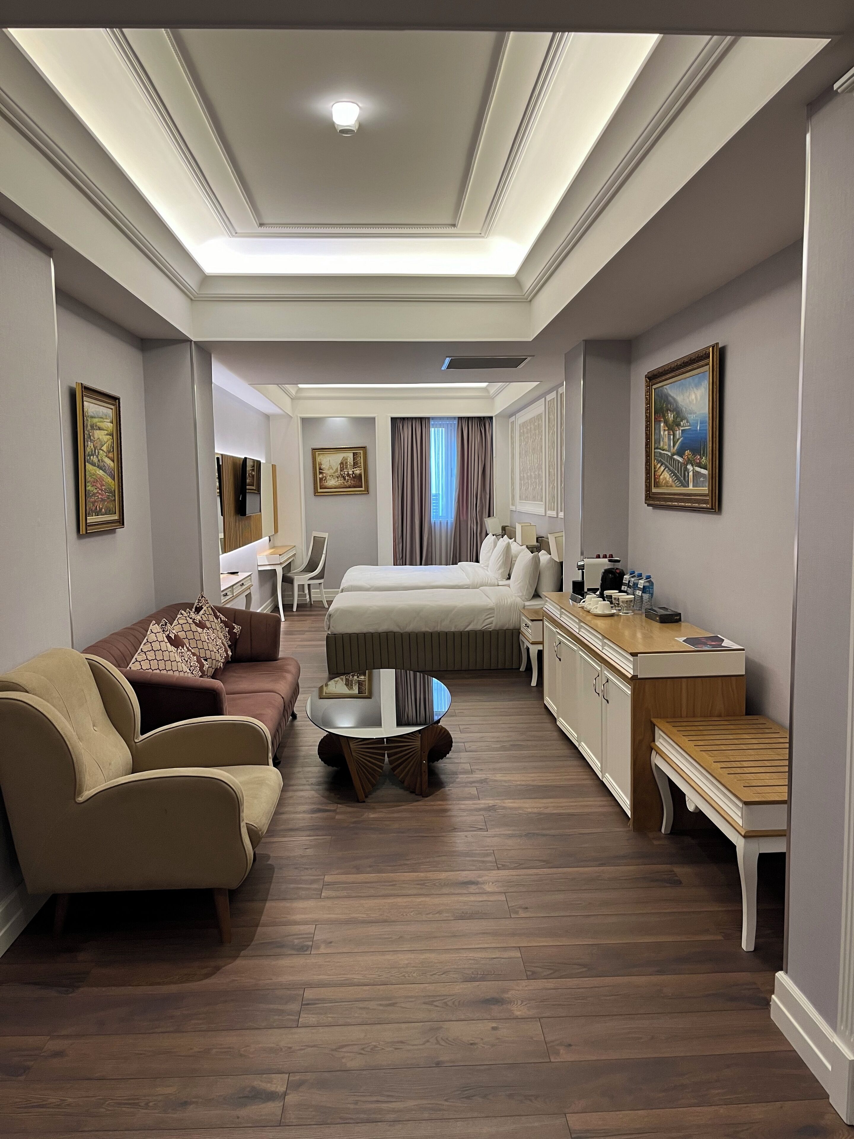 Een hotelkamer met een bed, een bank, een salontafel, een bureau en een televisie.