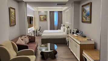 Een hotelkamer met een bed, een bank, een salontafel, een bureau en een televisie.