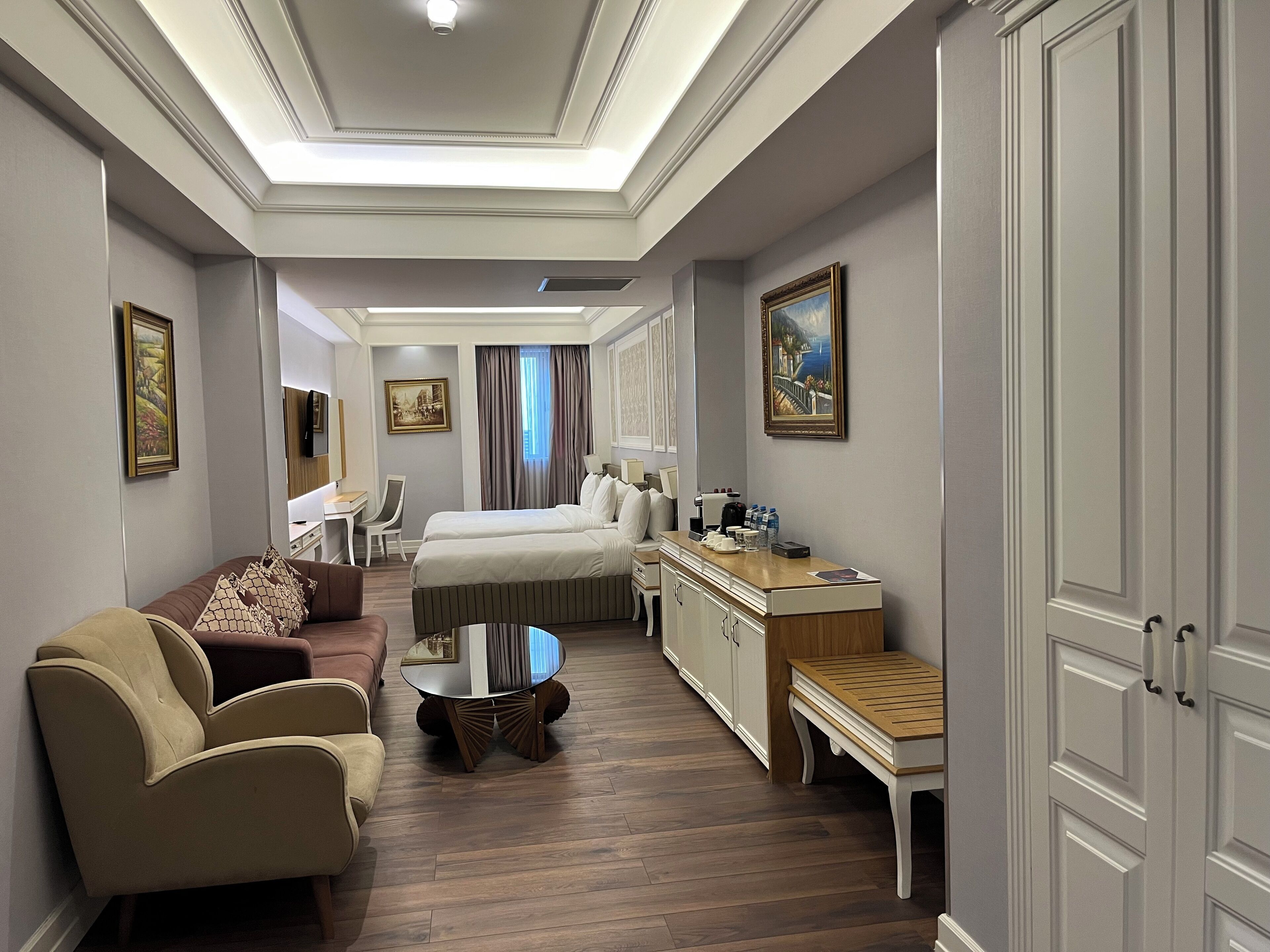 A hotel room with a bed, a desk, a sofa, and a dining table.