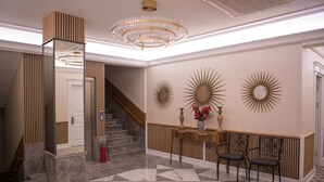 A lobby with a marble floor, a staircase, a reception desk, and decorative wall mirrors. - Theatrum Hotel Baku (Baku)