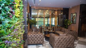 A lobby with tufted leather sofas, a glass partition, and a decorative plant wall. - Theatrum Hotel Baku (Baku)