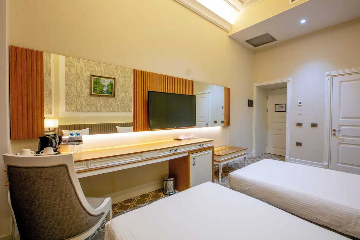 A hotel room with a bed, a desk with a TV, a chair, and a bathroom door.