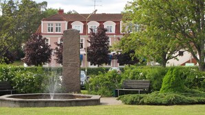 A park with a fountain, a stone monument, and a bench.