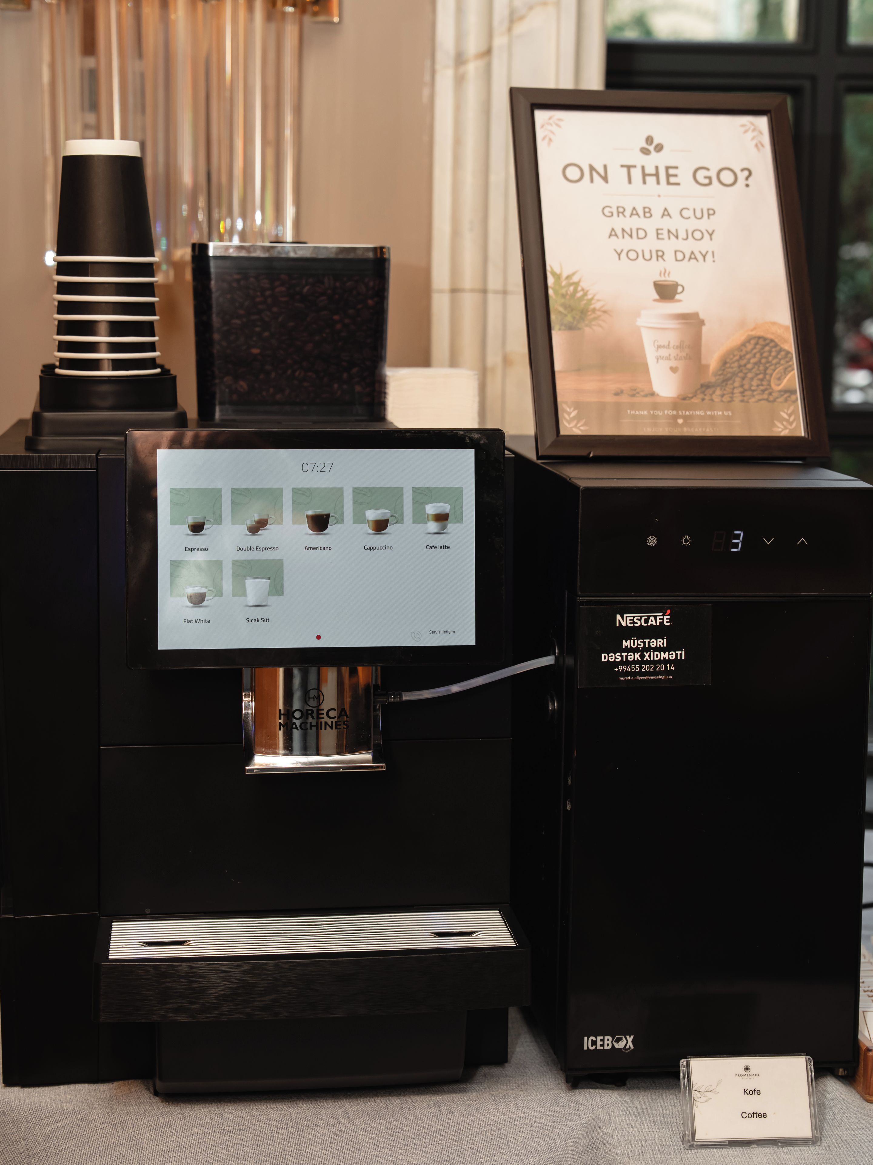 Una cafetera con pantalla digital y una taza de café a su lado.