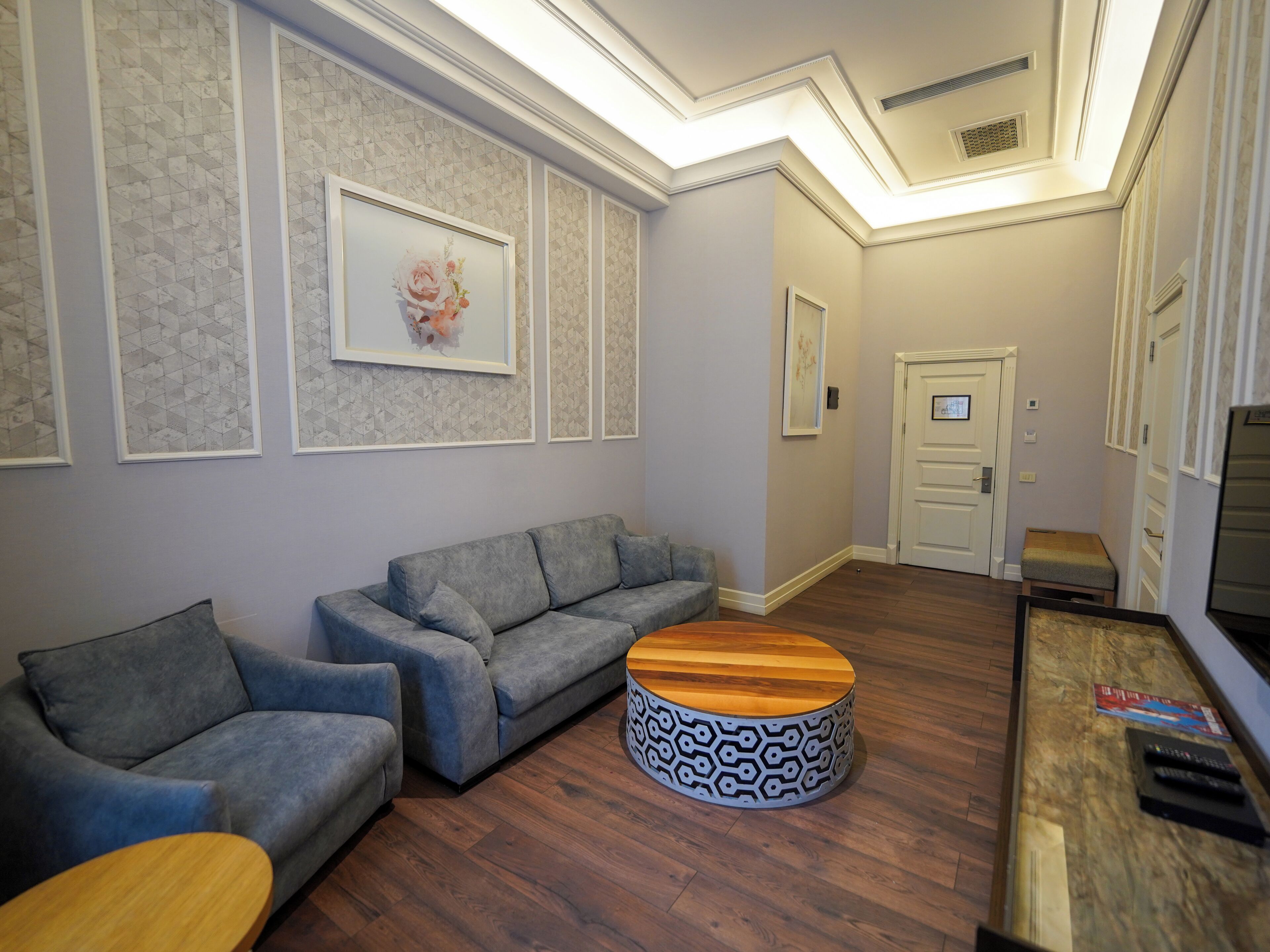 A modern living room with a grey sofa, a round coffee table, and a wooden side table.