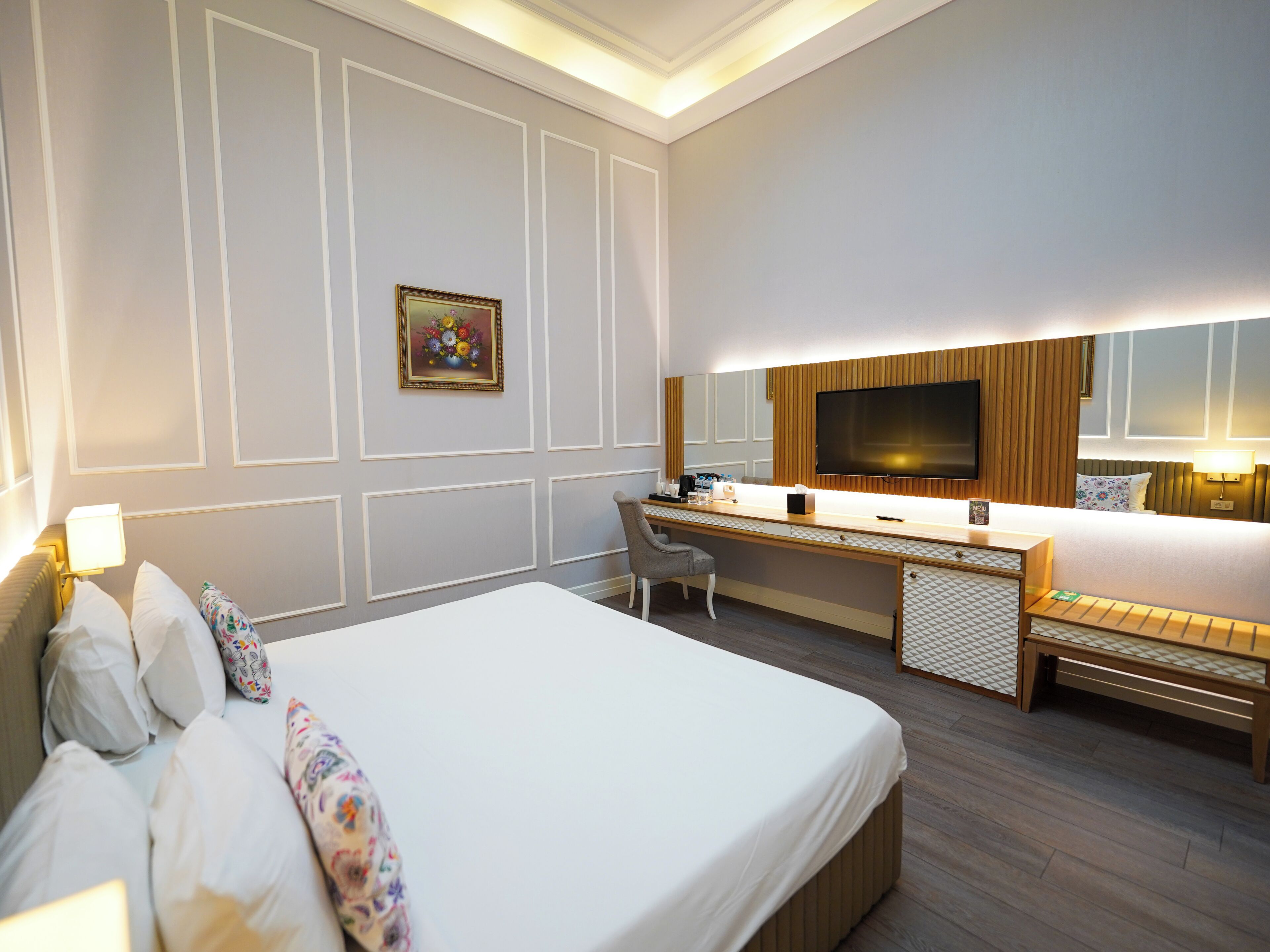 Ein Hotelzimmer mit einem großen Bett, einem Schreibtisch mit Stuhl, einem Fernseher und einem Nachttisch.