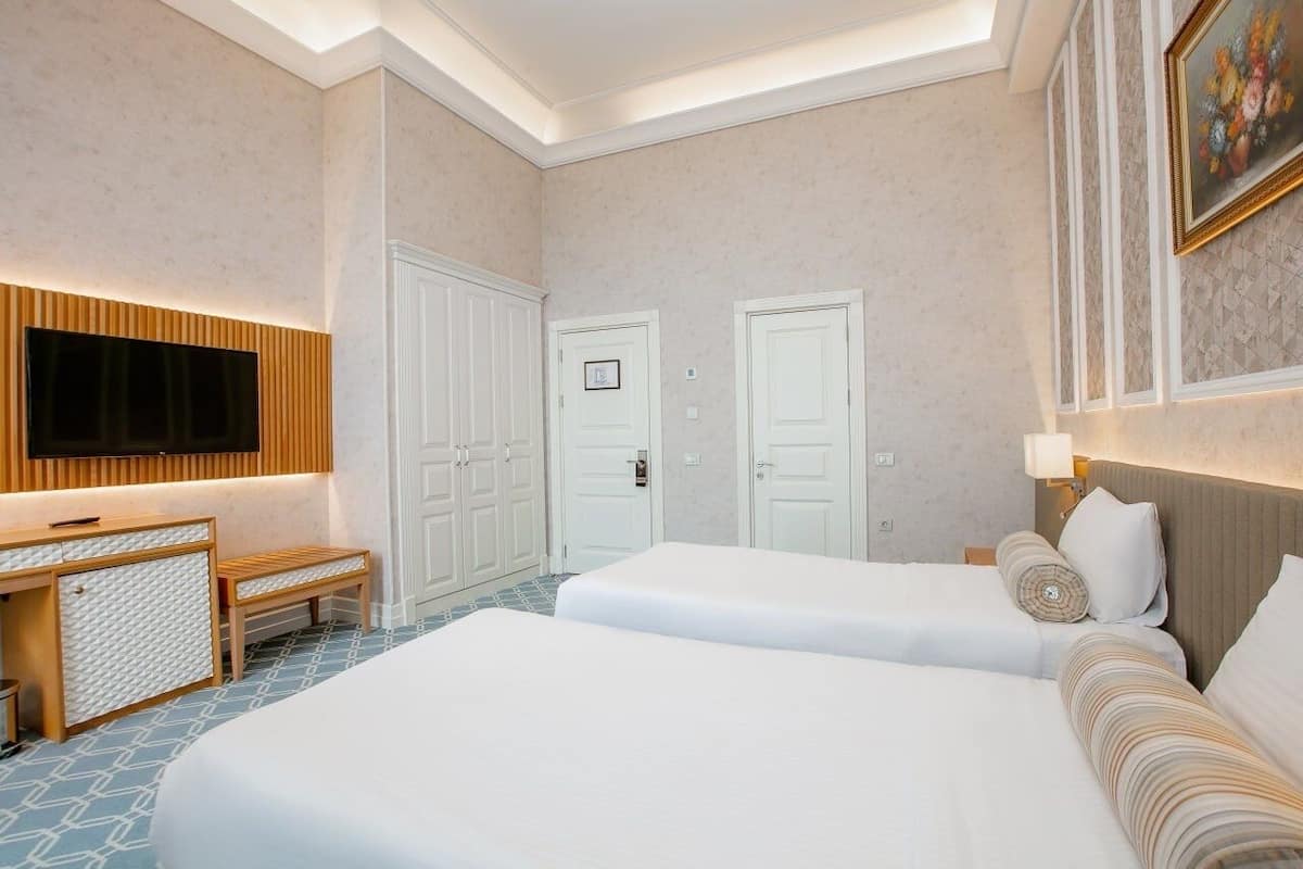 A hotel room with two beds, a TV, a desk, and a wardrobe.