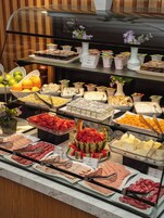 Een buffet met diverse gerechtjes, zoals fruit, kazen en vleeswaren.