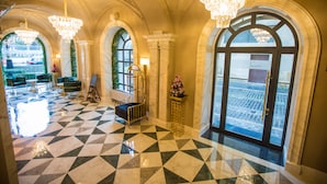 Rebedor d'hotel amb sòl de pissos, finestres apuntades, lluminàries i vista al carrer.