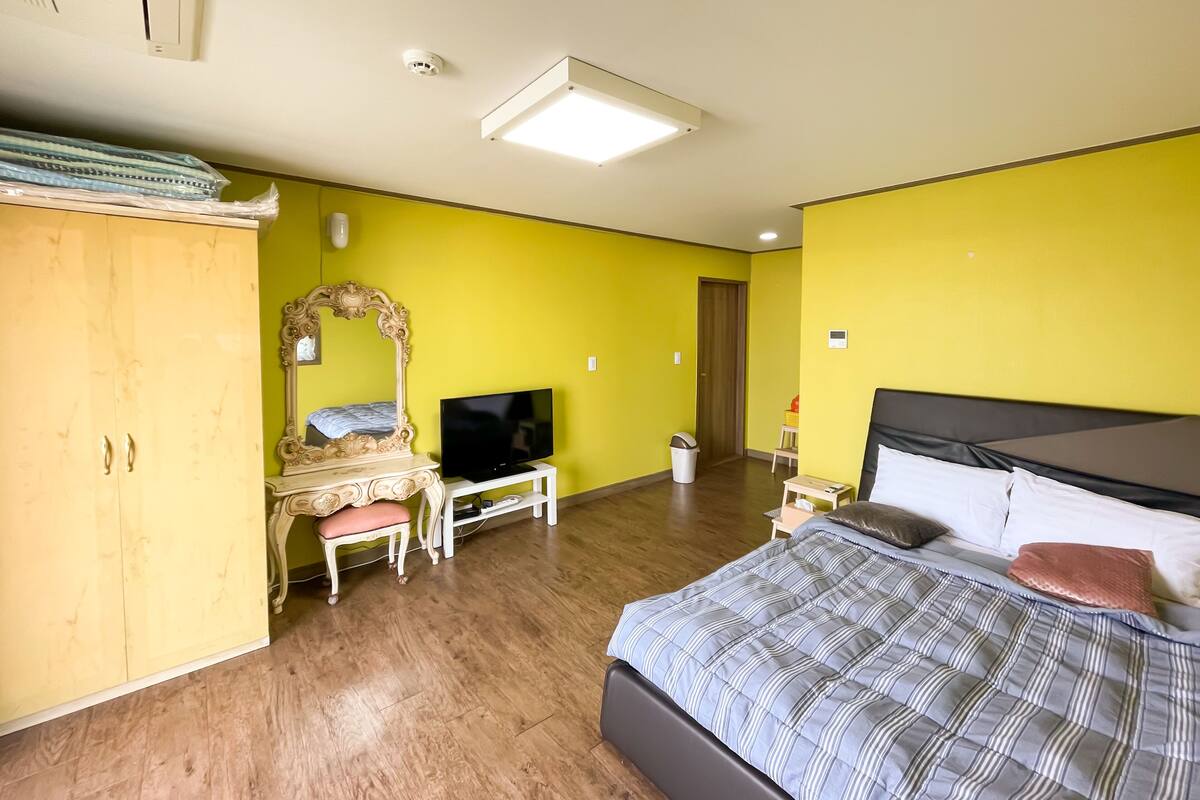 A bedroom with a bed, a TV, a wardrobe, and a mirror.