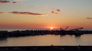 A sunset over a harbor with boats and industrial structures. - Gangneung Ocean Marina Pension - Hostel (Gangneung)