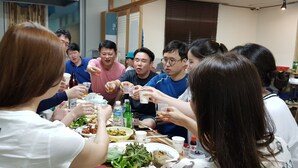 A group of people sitting around a table with food and drinks, in a room with a window and a door. - Gangneung Ocean Marina Pension - Hostel (Gangneung)