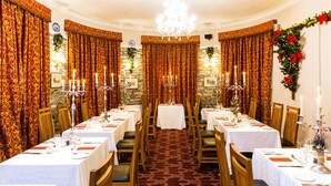 A formal dining room with long tables, chandeliers, and red patterned curtains. - Courtmacsherry hotel (Courtmacsherry)