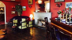 A bar area with a fireplace, seating, and a bar counter with beer taps. - Courtmacsherry hotel (Courtmacsherry)