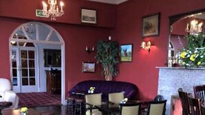 A dining area with a red wall, a chandelier, and a plant. - Courtmacsherry hotel (Courtmacsherry)