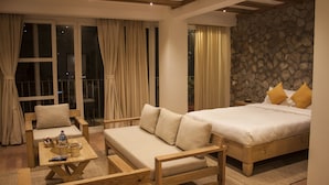 Un dormitorio con cama, sofá, mesa de madera y ventana con cortinas.