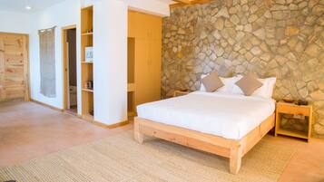 Un dormitorio con pared de piedra, estructura de cama de madera y mesita de noche.