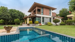 A modern two-story house with a swimming pool, surrounded by well-maintained lawns and various plants. - Pool Villa Pattaya by Passionata (Pattaya)