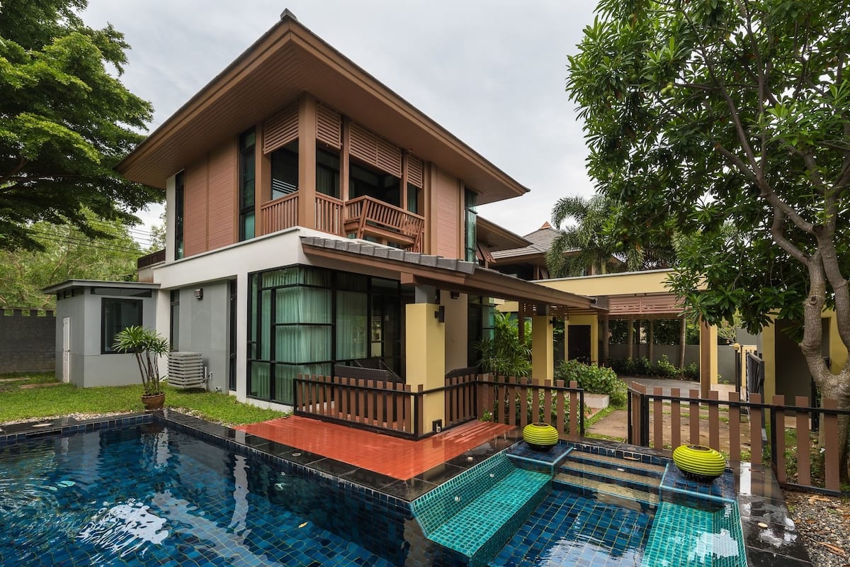 A two-story house with a swimming pool, a balcony, and a garden.