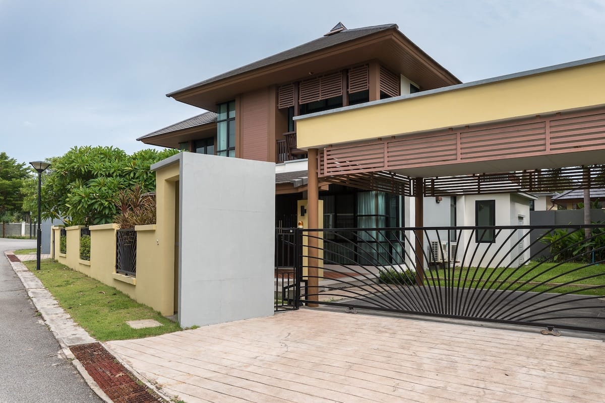 A modern two-story house with a flat roof, large windows, and a gated driveway.