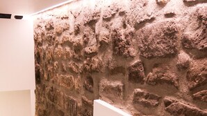 Una escalera con un muro de piedra texturizada a un lado y un muro blanco al otro.