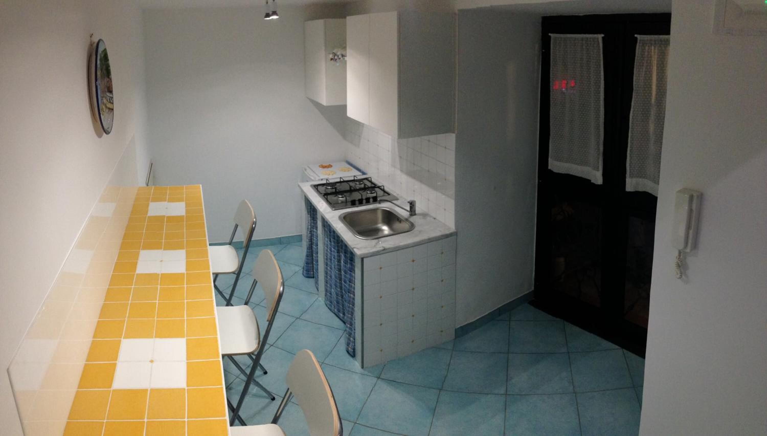 Una cucina compatta con zona pranzo, caratterizzata da un rivestimento piastrellato, un fornello e un lavandino.