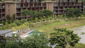 Et moderne hotel med flere etager, udendørs pool og frodig beplantning.